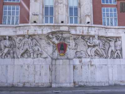Il basamento in pietra in corrispondenza del corpo centrale presenta una lunga decorazione ad opera dello scultore romano Omero Taddeini. L�altorilievo raffigura vari militanti fascisti e sotto quella che sembra essere la �Vittoria alata� � stato posto il simbolo della caserma, con il tipico pino verde sullo sfondo rosso (foto di Gennaro Gargiulo)